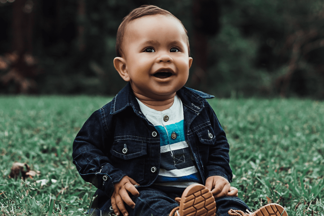 Child sitting in a field and smiling