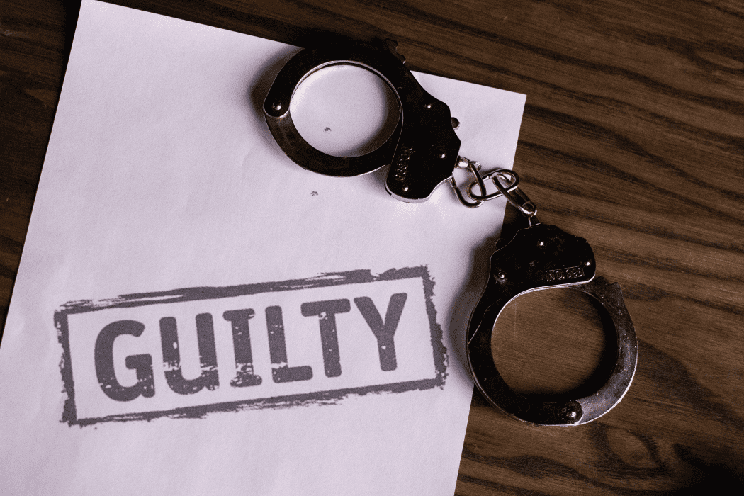 Pair of handcuffs on a piece of paper that reads "guilty"