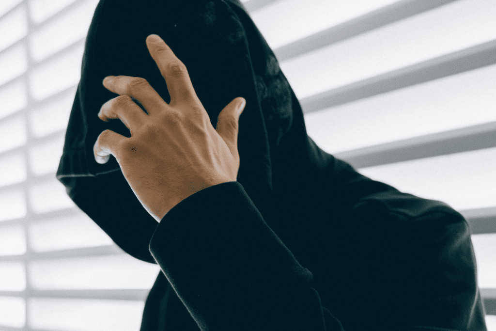 Man in dark hoodie covering face