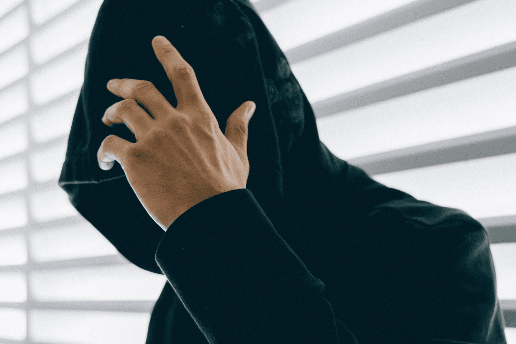 Man in dark hoodie covering face