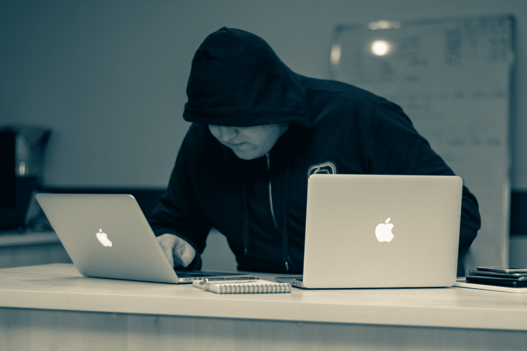 Man in hoodie working on two apple laptops