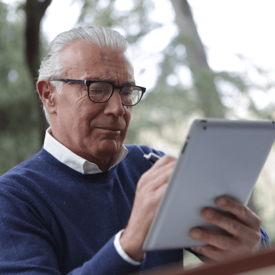 Man in blue sweater holding a white tablet