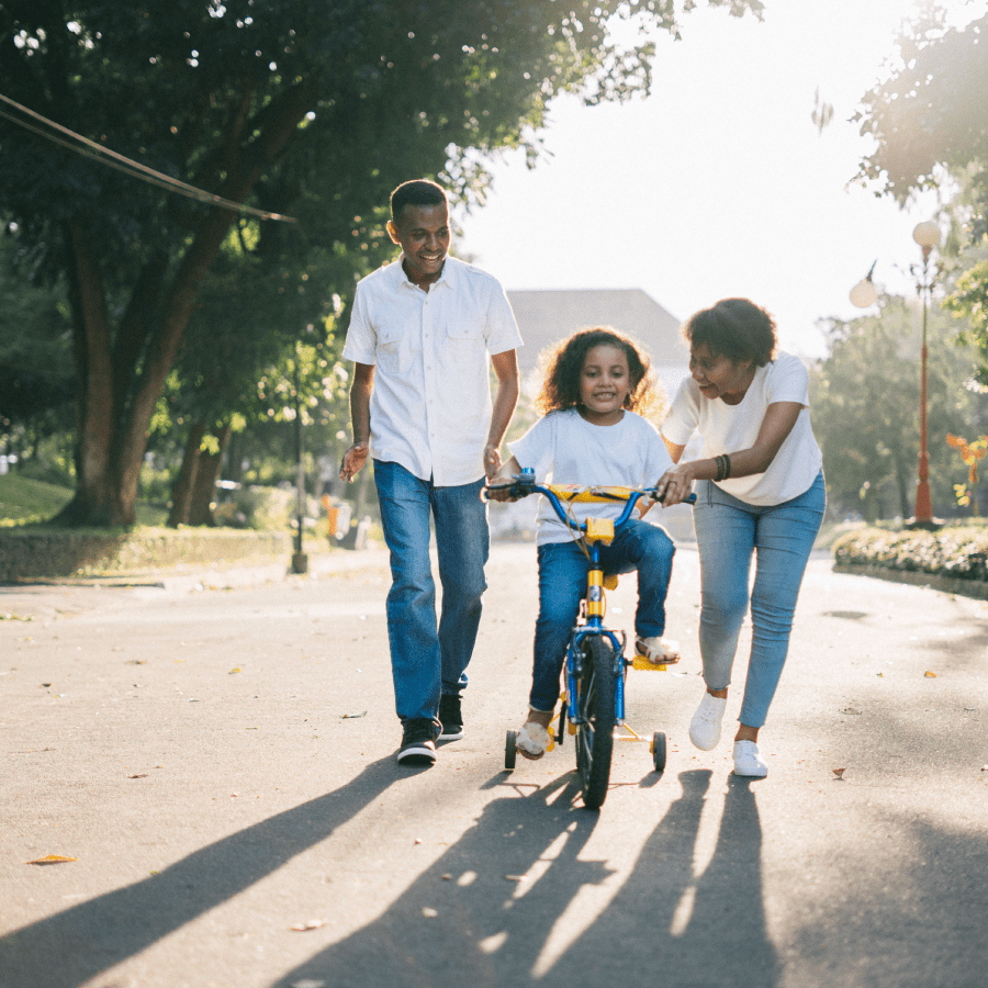 Mother and father teaching daughter how to ride a bike