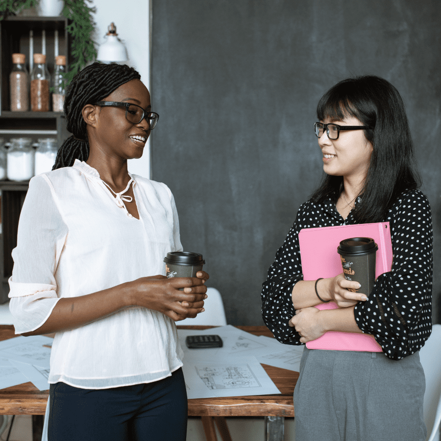 Two co-workers standing next to each other talking