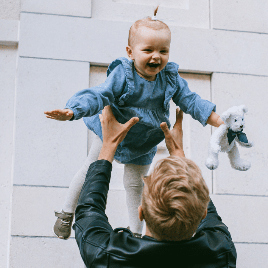 Father holding his daughter in the air above his head