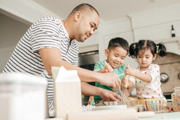 father and two children baking cookies