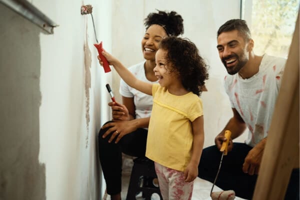 mother and father painting a wall with their child