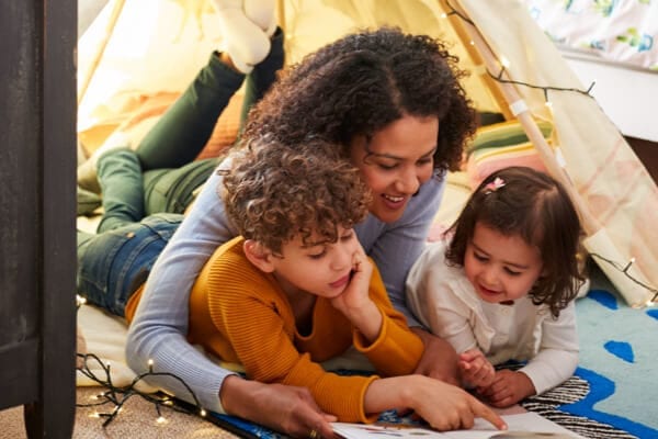 mother and two children sitting in a tent and reading