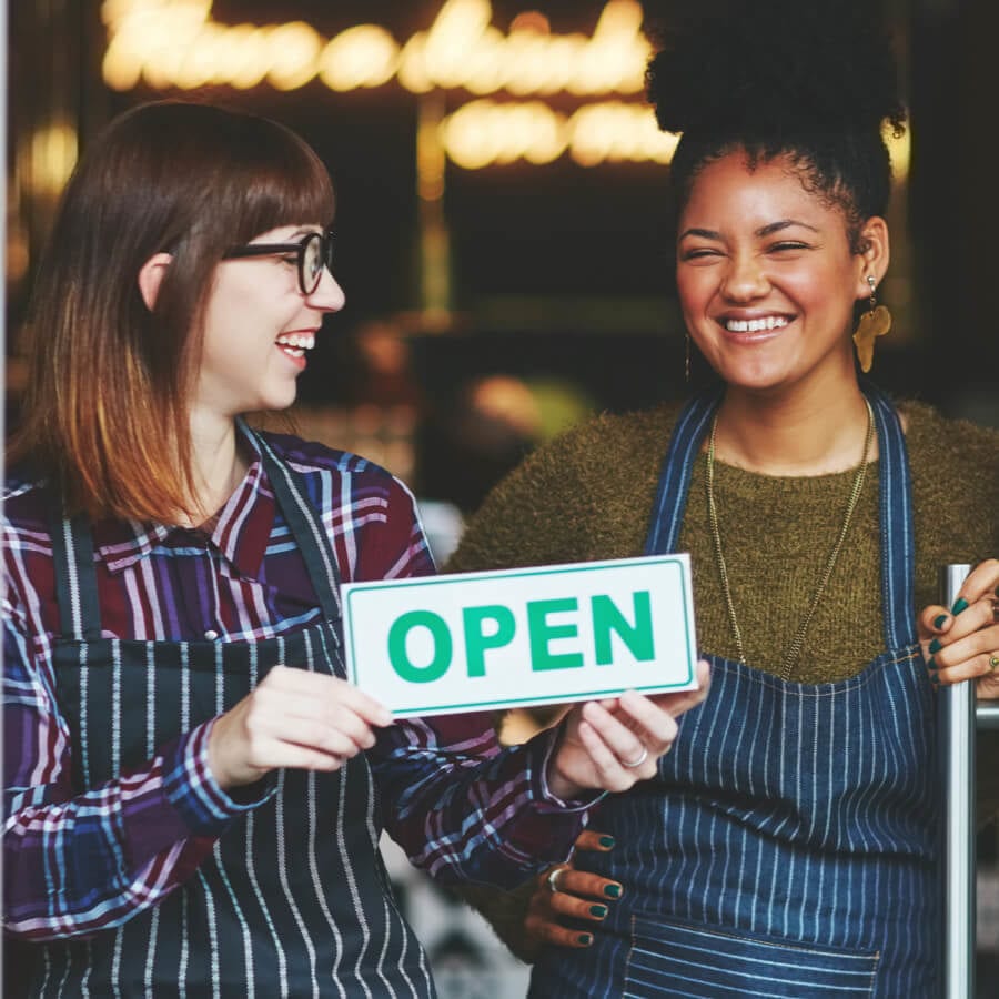 two employees holding an open sign