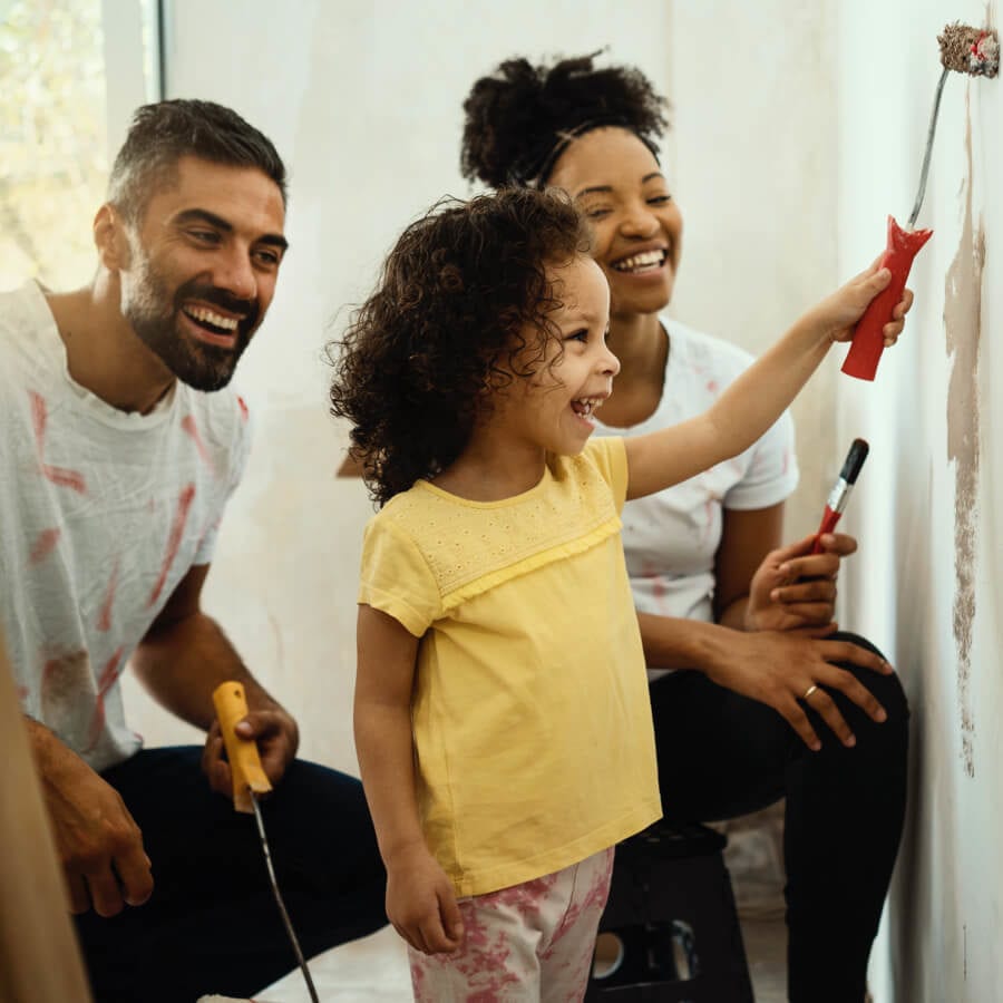 mother and father teaching child how to paint