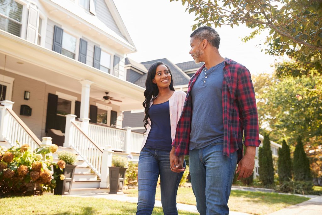 couple holding hands in front of a house