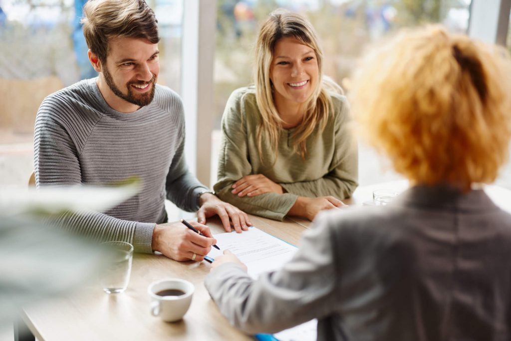 couple sitting at a table, signing documents with a lender