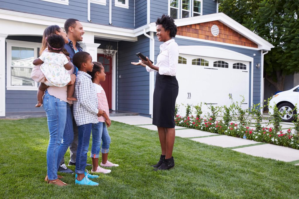 family talking to a professionally dressed woman in a yard