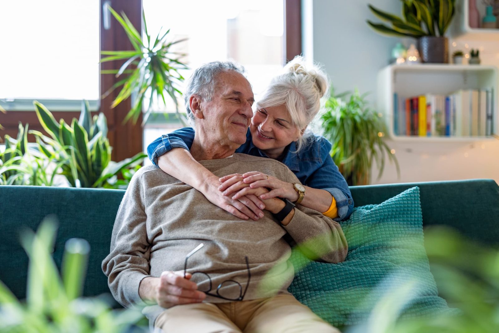 older couple cuddling in a room with plants