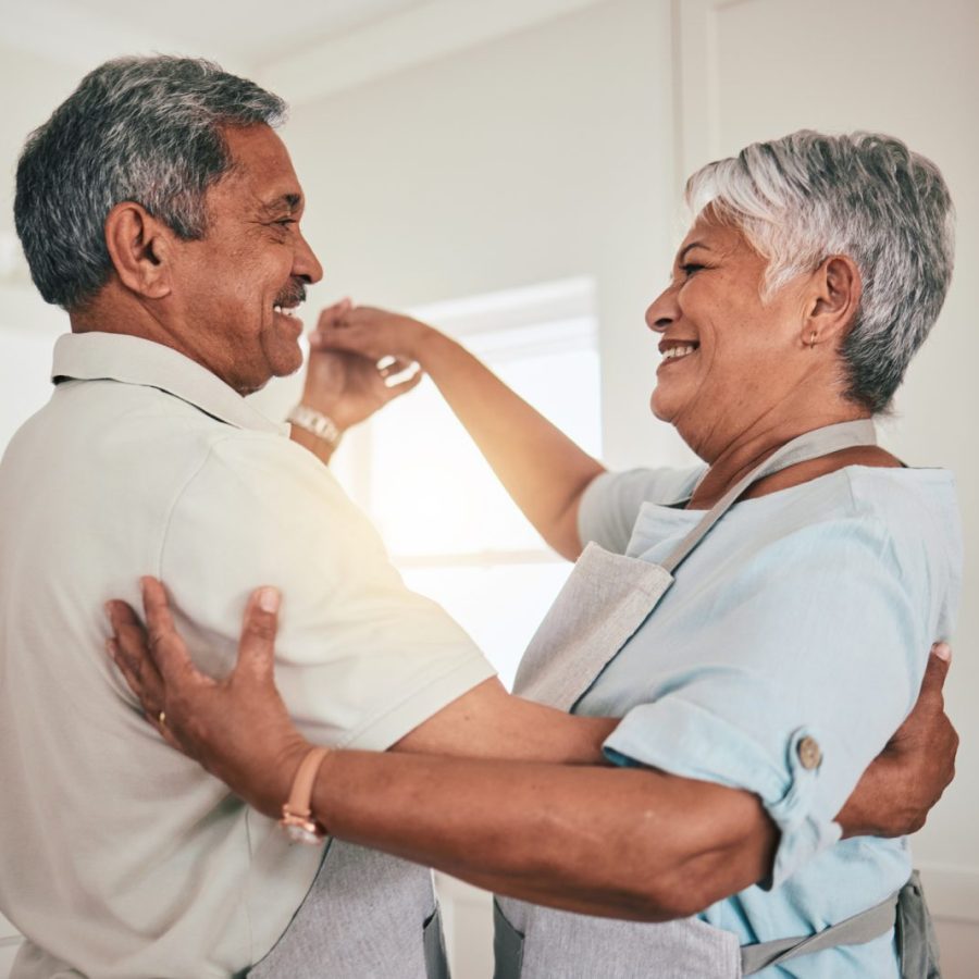 Couple dancing in the kitchen while smiling