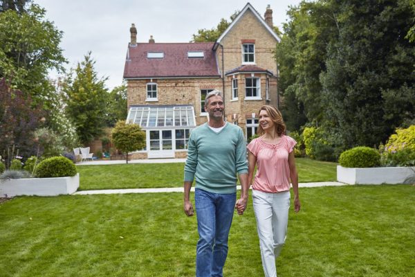 couple holding hands walking through their backyard