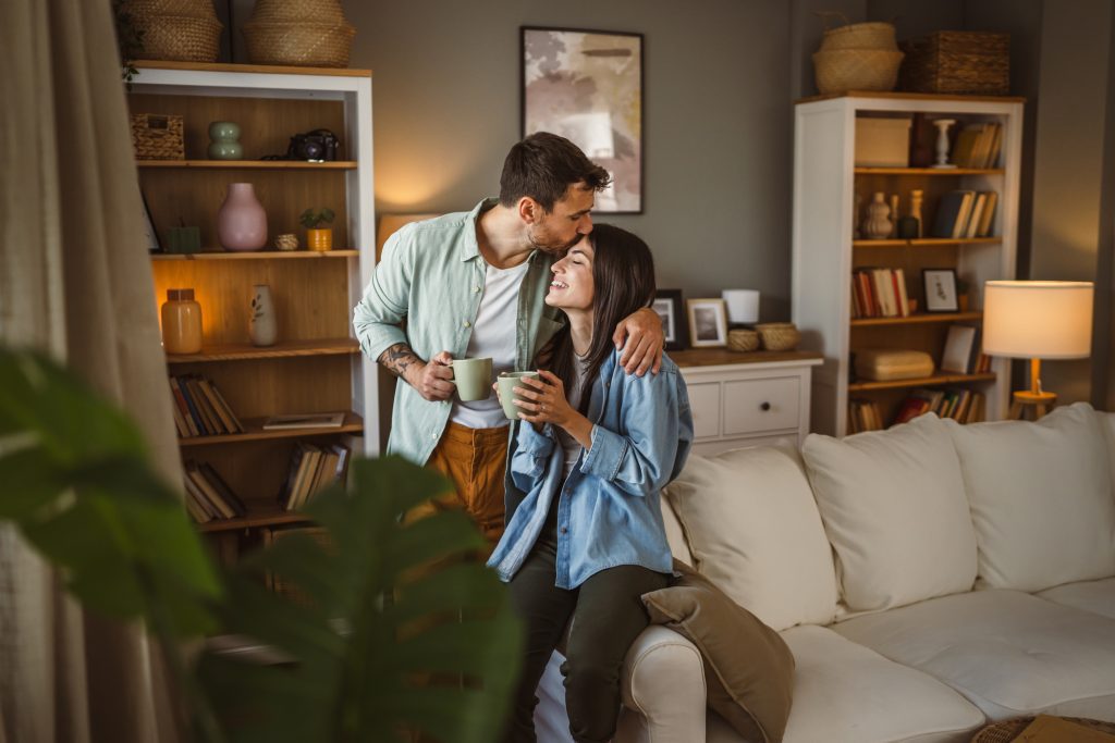A couple is sitting on the arm rest of their classic home.