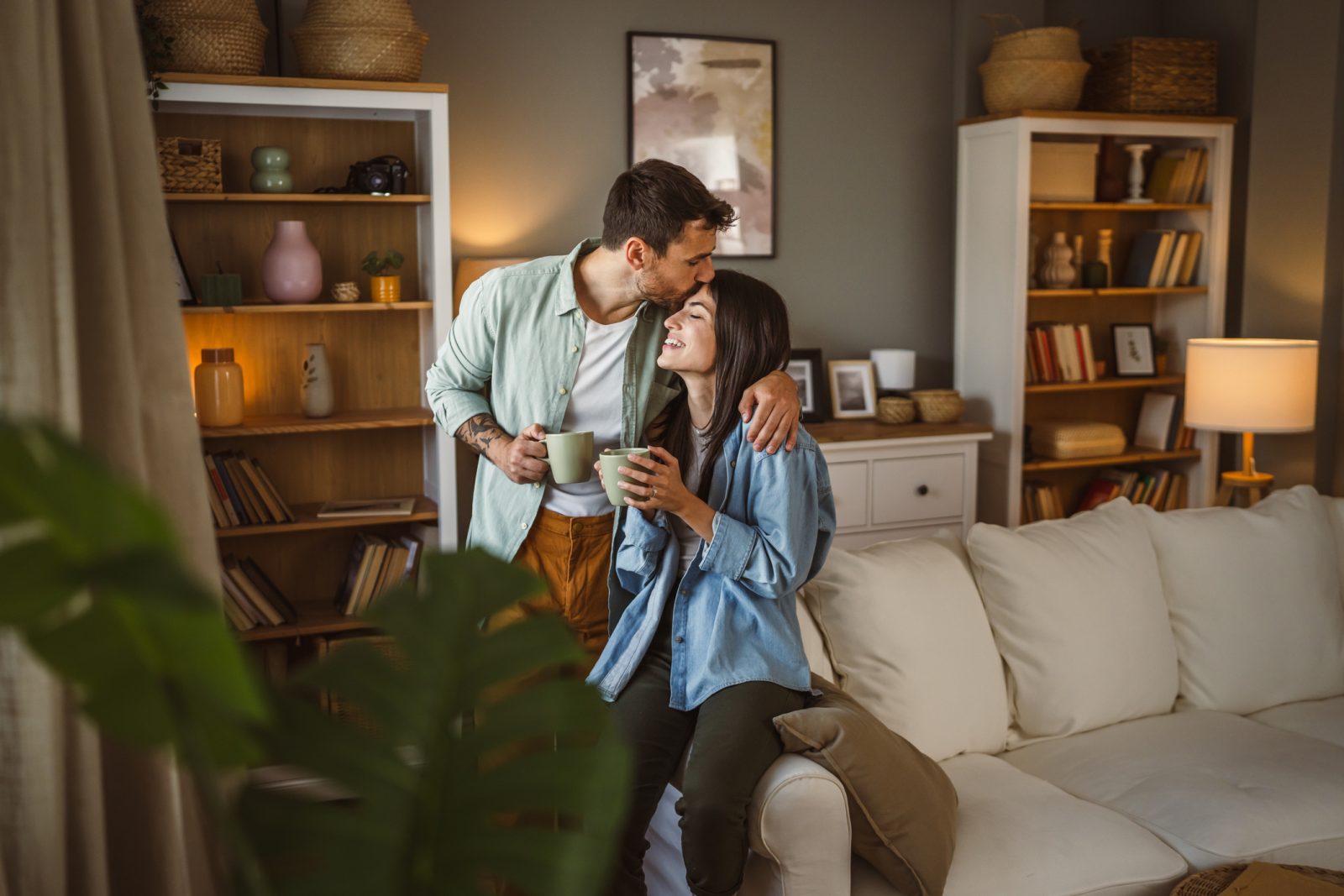 A couple is sitting on the arm rest of their classic home.