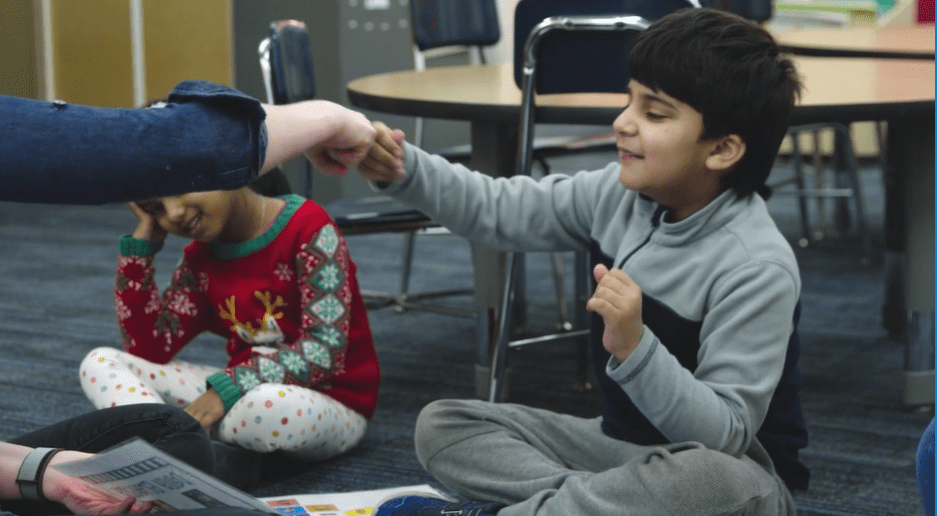 Child fist-bumping his teacher